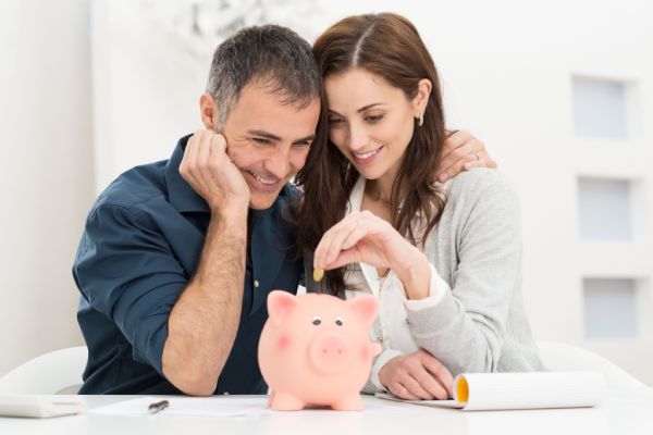 a couple looking a piggy bank discussing savings