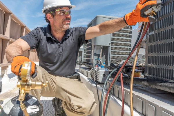 Técnico de climatización trabajando en la instalación de una nueva unidad condensadora en un tejado.