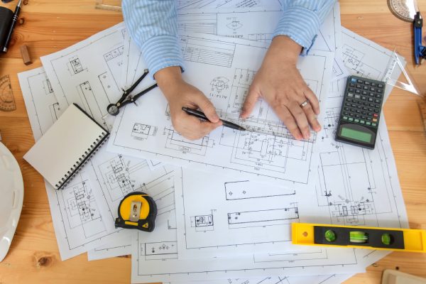 Architects man design planning construction projects at desk with blueprints.