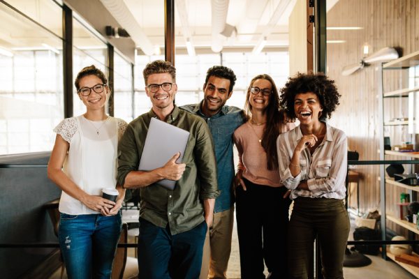 Portrait of creative business team standing together and laughing. Multiracial business people together at startup.