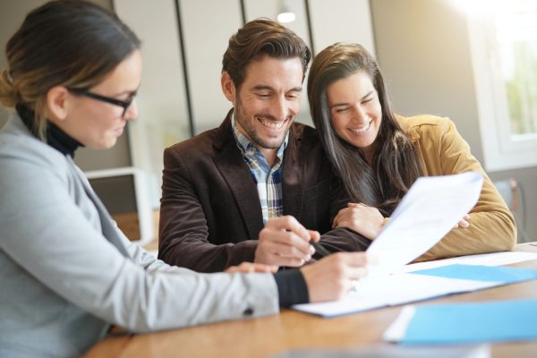 Attractive couple signing sales agreement with real estate agent