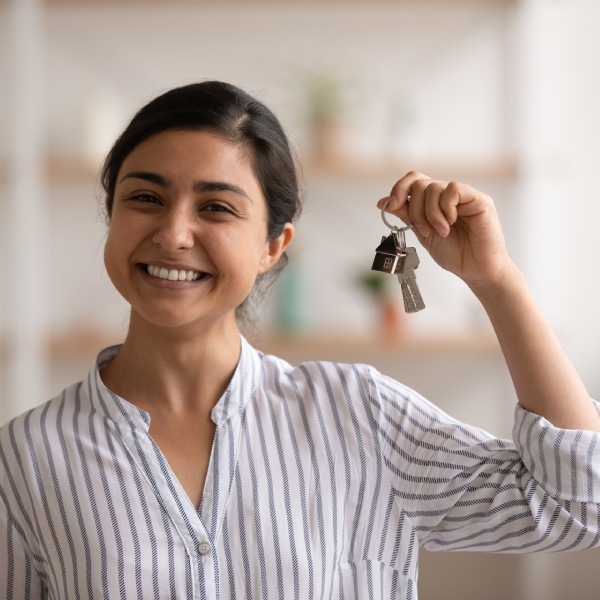 House of dream. Headshot portrait of excited indian female happy winner buyer renter tenant of new home apartment. Young mixed race woman proud homeowner looking at camera showing keys of modern flat