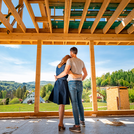 A couple examines a house under construction, reflecting on the 2025 real estate trends in Texas.