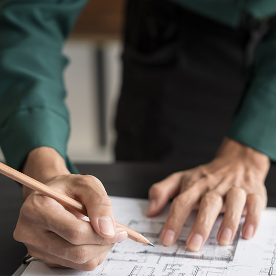 An individual holds a pencil, jotting down information on paper for commercial construction preparation.