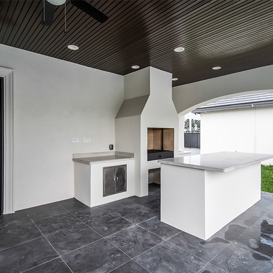 Outdoor kitchen featuring a ceiling fan and sink, perfect for summer gatherings in your custom home.