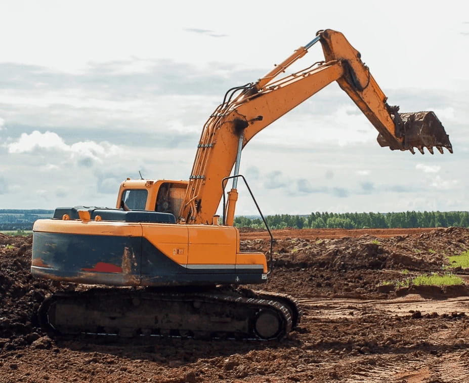 An excavator is actively digging in the dirt for a commercial construction project.