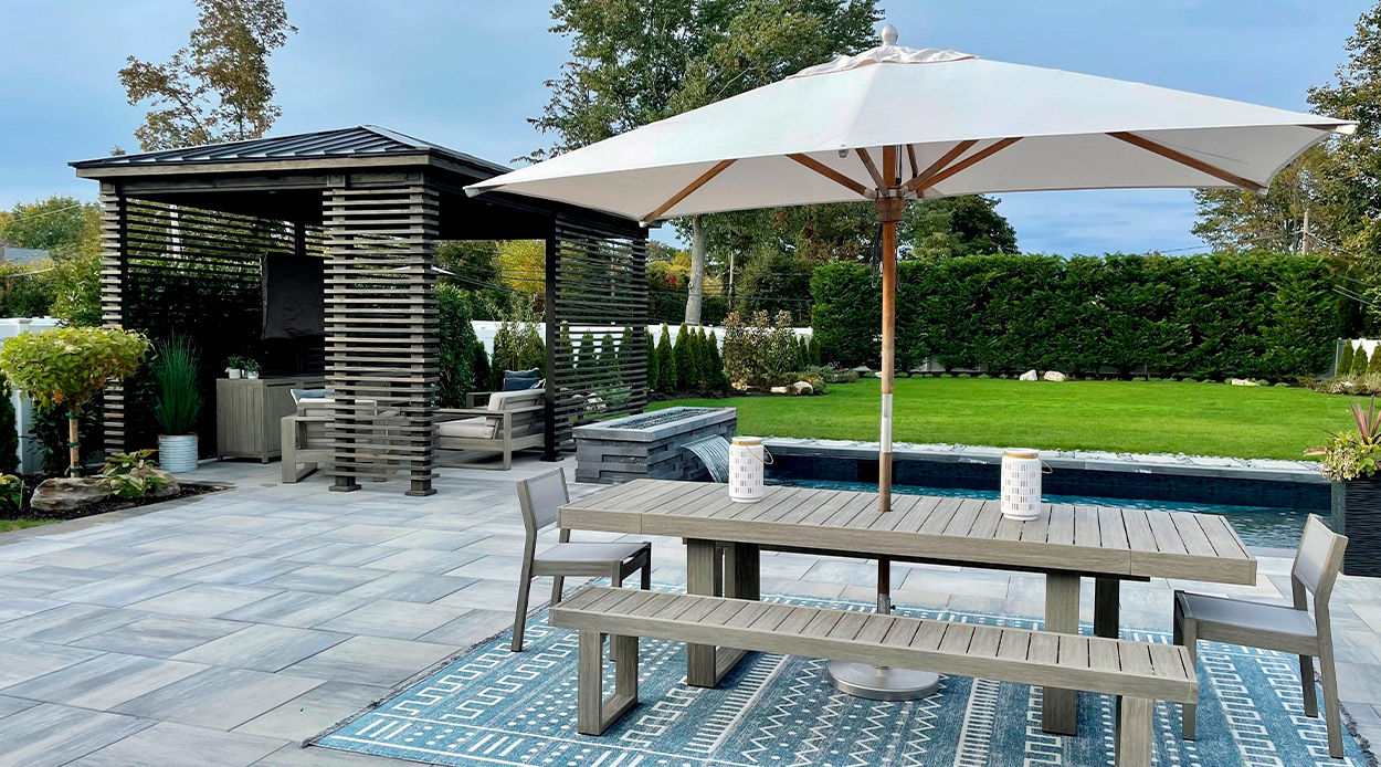A cozy patio featuring a table and chairs shaded by an umbrella, perfect for summer gatherings in your custom home.