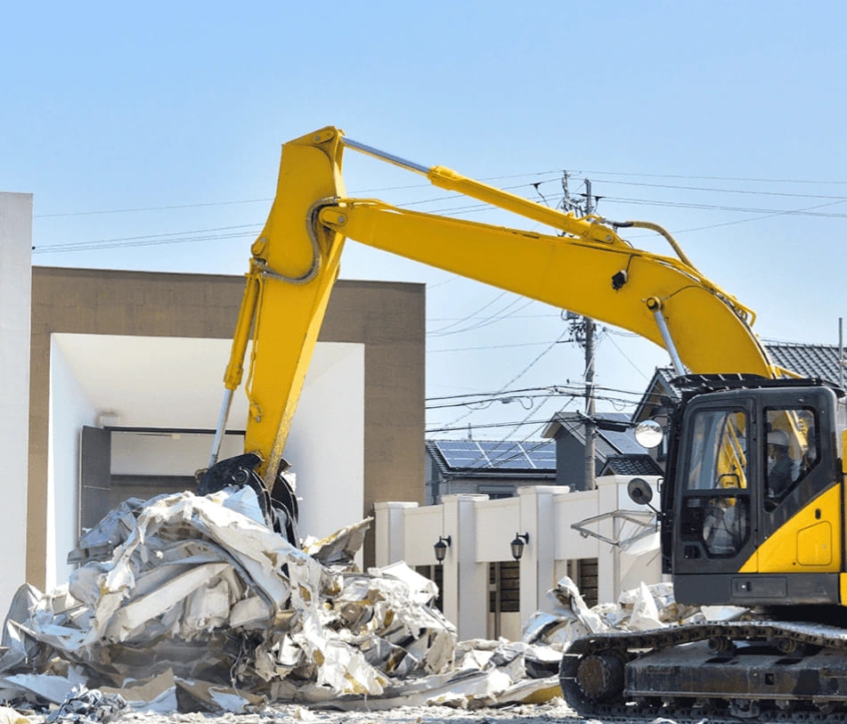 An excavator in yellow is actively working on a rubble pile, representing demolition services in McAllen.