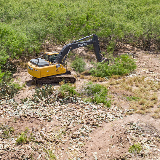 A yellow and black bulldozer is actively working on a field, part of land clearing for South Texas businesses.