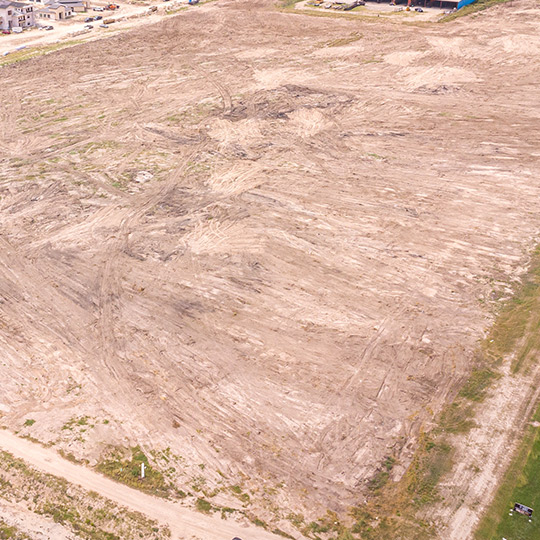 Overhead shot of a vast dirt field, highlighting land clearing opportunities for South Texas enterprises.