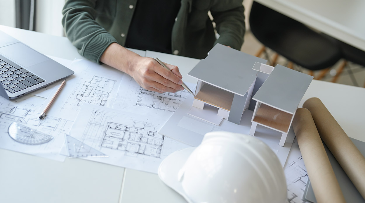 a person meticulously constructs a detailed model of a house, illustrating custom home design in McAllen, South Texas.