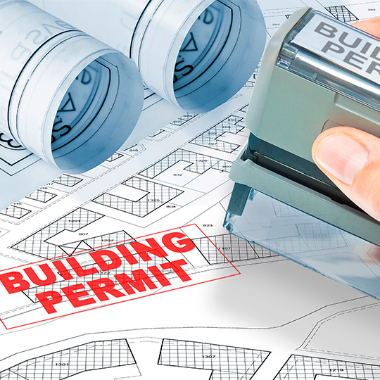 An individual applying a stamp to a building permit on a blueprint, indicating progress in custom home construction in McAllen.