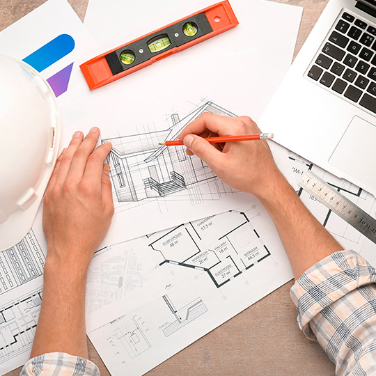 An individual in a hard hat uses a laptop to work on a project about building custom homes in McAllen, South Texas.