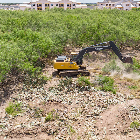 A bulldozer removes debris from a field, highlighting the need for expert land clearing services for McAllen businesses.