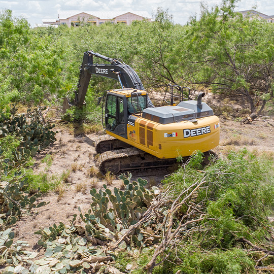 A bulldozer clears a tree, illustrating land clearing work for construction projects.