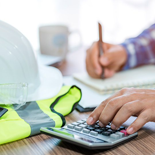 An individual uses a calculator to determine costs associated with a residential demolition project.