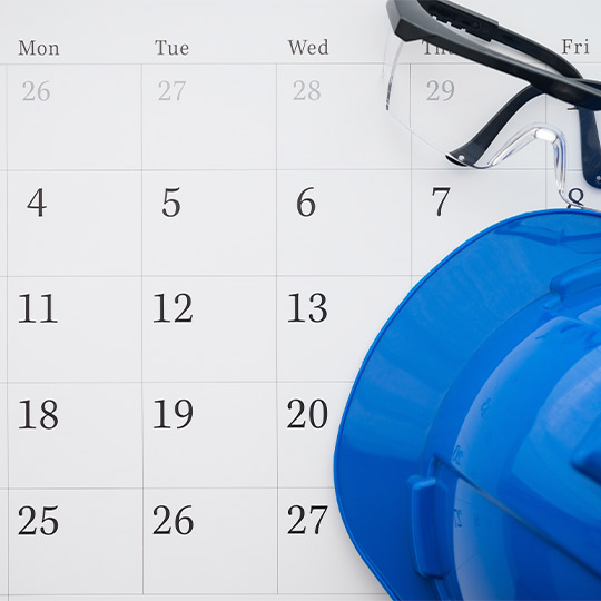 A hard hat, safety glasses, and a calendar are placed on a desk, indicating preparations for residential demolition work.