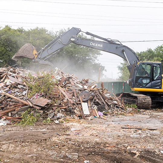 A bulldozer is working to remove debris from a rubble pile during a teardown operation.