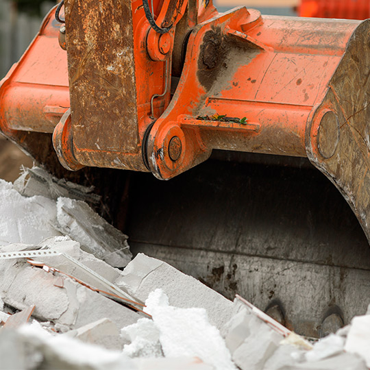 A bulldozer is actively removing rubble at a construction site, part of the teardown process for future building projects.
