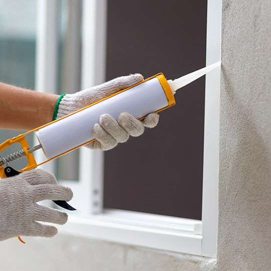 A gloved individual in a white shirt constructs a window frame with a tool, reflecting 2026 exterior design trends for McAllen, TX.