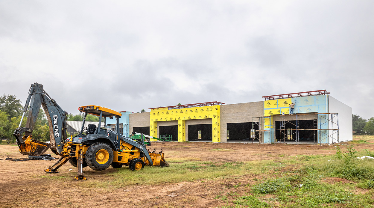 A parked tractor in front of a commercial construction site, indicating ongoing building activities in the area.